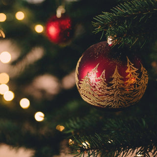 Christbaumkugel an einem geschmückten Tannenbaum.