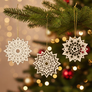 Christbaumschmuck „Eissterne“ im 3er Set aus Naturholz (8 cm), filigran gearbeitete Sternornamente am Weihnachtsbaum aufgehängt, umgeben von grünen Tannenzweigen und warm leuchtenden Lichtern im Hintergrund.