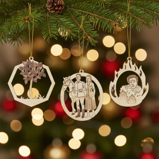 Baumbehang „Drei Haselnüsse für Aschenbrödel®“ Limited Edition 2024 im 3er Set, filigrane Holzornamente mit farblich abgesetzten Motiven (Baum, Figuren mit Pferd und Märchenszene) am Weihnachtsbaum, umgeben von Tannenzweigen, Zapfen und warmen Lichterketten.
