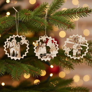 Baumbehang „Drei Haselnüsse für Aschenbrödel®“ Limited Edition 2025 im 3er Set, filigrane Holzornamente mit farblich abgesetzten Märchenszenen am Weihnachtsbaum, dekoriert mit Tannenzweigen und warm leuchtenden Lichtern im Hintergrund.