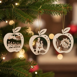 Baumbehang „DEFA-Schneewittchen“ im 3er Set, einfarbig abgesetzte Holzornamente in Apfelform mit filigranen Märchenszenen, am Weihnachtsbaum aufgehängt, umgeben von grünen Tannenzweigen und warmen Lichterketten im Hintergrund.