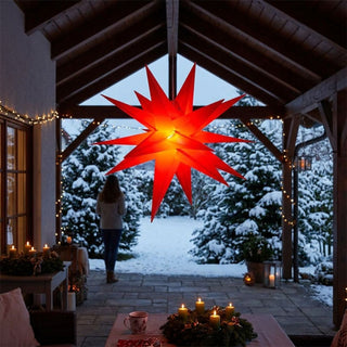 Roter LED-Adventsstern für Außen von HGD mit einem Durchmesser von 60 cm, aufgehängt unter einer überdachten Terrasse. Der große, mehrzackige Stern leuchtet in kräftigem Rot mit warmem Licht im Zentrum und bildet den Blickfang einer winterlichen Szenerie. Im Hintergrund sind verschneite Tannen, weihnachtliche Lichterketten und dekorierte Kerzenarrangements zu sehen, die eine festliche und gemütliche Atmosphäre schaffen.