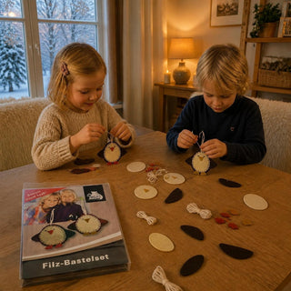 Bastelset-Filz „Pinguine“ im 2er Set. Zwei Kinder basteln an einem Tisch niedliche Pinguin-Anhänger aus Filz. Zu sehen sind die einzelnen Filzteile, Schnüre und die Verpackung des Bastelsets. Im Hintergrund sorgen ein verschneites Fenster und warmes Licht für eine gemütliche Winterstimmung.