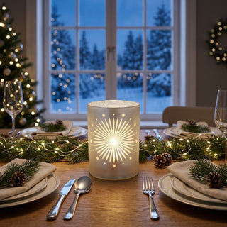 LED Dekoglas mit Sterndekor in Satin-Weiß und Silber, ca. 10 cm groß, mit filigranem Sternmuster, warmweiß leuchtend, mit integrierter Timerfunktion, als stimmungsvolle Tischdekoration in weihnachtlich gedecktem Ambiente platziert.