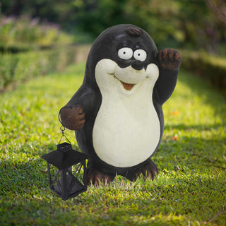 Dekorative Gartenfigur Maulwurf aus Kunststein in Schwarz‑Weiß, steht auf grünem Rasen und hält eine schwarze Laterne mit LED‑Solar‑Licht – witzige Gartendeko für den Außenbereich.