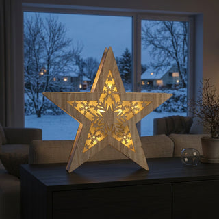 LED-Weihnachtsstern „Schneeflocke“ (35 cm) mit Timer, naturfarbene Holzoptik mit filigranem Schneeflockenmotiv, warm leuchtend vor winterlicher Fensterkulisse platziert.