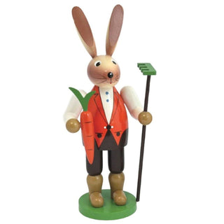 Farbiger Osterhase aus Holz mit Karotte und Rechen in der Hand.