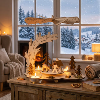 Weihnachtspyramide „Wald“ aus naturbelassenem Holz (23 cm) für drei Teelichter mit Flügelrad. Szene mit Rehen, Tannenbäumen und kleinem Haus unter einem geschwungenen Holzbogen. Auf einer Kommode vor verschneitem Fenster, stimmungsvoll mit Kerzenlicht dekoriert.