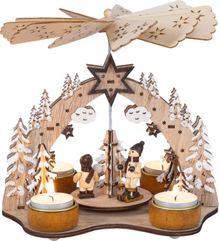 Weihnachtspyramide aus Holz für 4 Teelichte mit Wintermotiv, verschneiten Tannenbäumen, Figuren auf Skiern und Flügelrad, 21 cm.