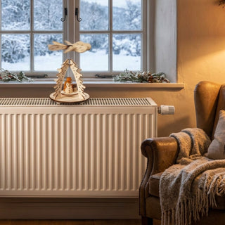 Weihnachtspyramide „Wärmespiel Schneemann“ aus naturbelassenem Holz (12 cm) mit Flügelrad. Kleine Szene mit Schneemann unter stilisierten Tannenbäumen, die durch aufsteigende Wärme in Bewegung kommt. Auf einer Fensterbank bzw. Heizung vor verschneiter Winterlandschaft, gemütlich dekoriert.
