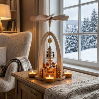 Weihnachtspyramide „Schneemänner im Winterwald“ aus naturbelassenem Holz (30 cm) für vier Teelichter mit Flügelrad. Offene Bogenform mit Schneemann-Figuren und Tannenbäumen. Auf einem Tisch vor verschneitem Fenster, warm beleuchtet und winterlich dekoriert.
