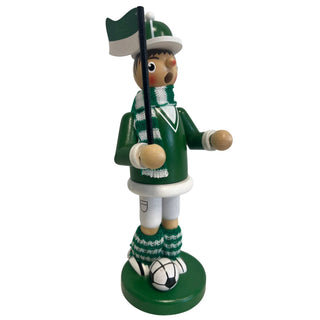 Räuchermännchen „Fußballer“ aus Holz, ca. 23 cm groß, in grüner Farbgestaltung aus schräger Seitenansicht. Die Figur steht auf einem runden grünen Sockel neben einem schwarz-weißen Fußball, trägt ein grünes Outfit mit weißem Detail sowie einen grün-weiß gestreiften Schal und passende gestrickte Beinwärmer und hält eine grün-weiße Fahne an einem schwarzen Stab.