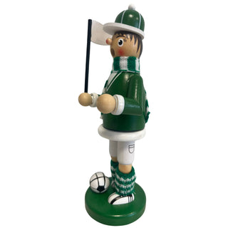 Räuchermännchen „Fußballer“ aus Holz, ca. 23 cm groß, in grüner Farbgestaltung aus seitlicher Perspektive. Die Figur steht auf einem runden grünen Sockel neben einem schwarz-weißen Fußball, trägt ein grünes Outfit mit weißem Detail sowie einen grün-weiß gestreiften Schal und gestrickte Beinwärmer und hält eine kleine weiße Fahne an einem schwarzen Stab.