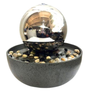 Kugelbrunnen aus Edelstahl mit LED, bestehend aus einer glänzenden, spiegelnden Metallkugel, über deren Oberfläche Wasser gleichmäßig nach unten fließt. Die Kugel sitzt in einer runden, grauen Schale, die mit kleinen dekorativen Steinen gefüllt ist. Das Produkt ist freigestellt vor hellem Hintergrund dargestellt und zeigt die klare Form sowie die reflektierende Oberfläche des Brunnens ohne weitere Umgebung.