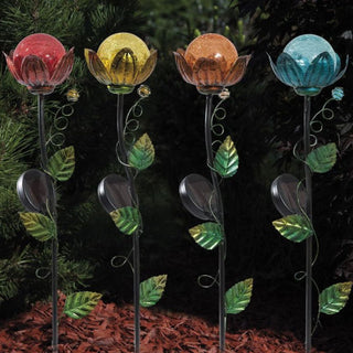 Vier solarbetriebene Gartenstecker in Blumenform mit farbigen Glaskugeln in Rot, Gelb, Orange und Blau, aufgestellt im Garten.