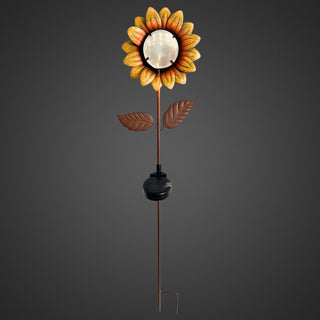 Gartenstecker in Form einer Sonnenblume mit gelb‑orangenen Blütenblättern und beleuchteter, spiegelnder Mitte mit Tunnellichteffekt. Brauner Metallstab mit zwei Blättern und integriertem Solar‑LED‑Modul. Gesamthöhe 84 cm, freistehend vor dunklem Hintergrund.