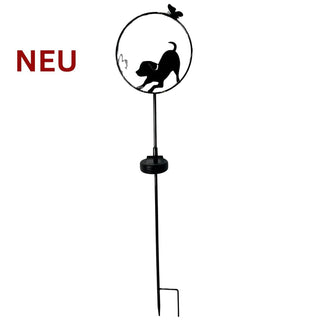 Gartenstecker aus Metall mit spielender Hunde‑Silhouette in dekorativer Darstellung. Der Hund ist in Bewegung dargestellt und wirkt verspielt. Ein integriertes Solar‑LED‑Licht sorgt bei Dunkelheit für dezente Beleuchtung. Am Metallstab befindet sich das Solar‑Modul. Gesamthöhe 84 cm, zum Einstecken in den Boden.