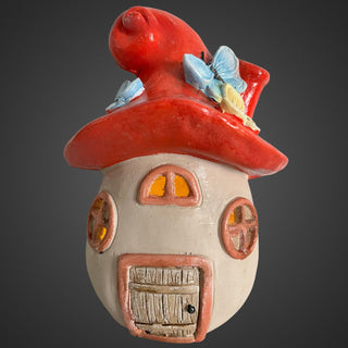 Dekohaus in Pilzform mit rotem Dach und Schmetterlingen, auf weißem Hintergrund. beleuchtet 