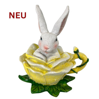 Dekofigur eines weißen Osterhasen, der aus einer gelben Blüte schaut, farbig, 12 cm hoch.