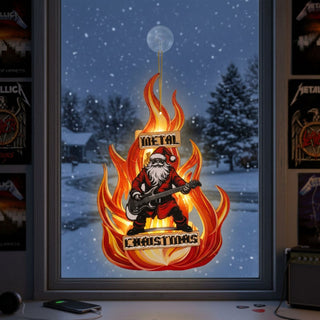 Fenster mit Blick auf eine verschneite Landschaft bei Nacht; in der Mitte des Fensters hängt ein dekorativer Anhänger mit Flammenmotiv. Darauf ist eine Weihnachtsmann-Figur dargestellt, die eine elektrische Gitarre spielt. Um die Figur lodern stilisierte orange-rote Flammen, und ober- sowie unterhalb stehen die Worte „METAL“ und „CHRISTMAS“.  Innenrahmen des Fensters wird von Musik‑Postern an den Seiten flankiert, und auf der Fensterbank liegen ein Smartphone und kleine Gegenstände.