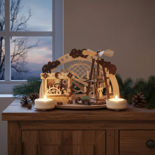 Kerzenhalter aus naturfarbenem Holz für zwei Teelichte mit Motiv „Backstübchen Weihnachtsmarkt“, auf einer Fensterbank dekoriert. Die detailreiche Szene zeigt ein kleines Backhüttchen mit Figuren, ein Karussell sowie winterliche Elemente, umrahmt von einem Bogen mit Sternen und Schneemotiven. Zwei Teelichter links und rechts sorgen für warmes Licht und beleuchten die filigranen Details; im Hintergrund ist ein Fenster mit winterlichem Abendhimmel zu sehen, ergänzt durch Tannenzweige und Zapfen.
