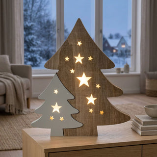 LED Diorama „Doppel-Weihnachtsbaum“ (40 cm) in naturfarbener Holzoptik, warmweiß beleuchtet, mit ausgeschnittenen Sternmotiven, dekorativ als stimmungsvolle Winter- und Tischdekoration vor verschneiter Fensterkulisse.