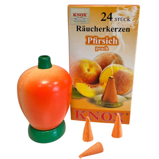 Farbiges Räuchermännchen in Pfirsichform mit grünem Sockel, daneben Packung Räucherkerzen mit Pfirsich-Duft sowie einzelne Räucherkerzen, dekoratives fruchtiges Design, Höhe ca. 8 cm.