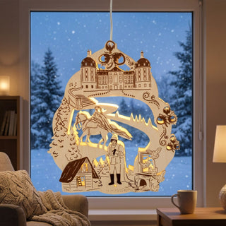 LED‑Fensterbild aus naturfarbenem Holz mit Motiv „Drei Haselnüsse für Aschenbrödel®“, warm beleuchtet und am Fenster aufgehängt. Die detailreiche Szene zeigt ein Schloss im oberen Bereich sowie mehrere Figuren, darunter eine Person auf einem Pferd und weitere Märchenelemente, umgeben von Tannen und dekorativen Ornamenten. Im Hintergrund ist eine verschneite Winterlandschaft zu sehen; im Innenraum stehen ein Sessel mit Decke und eine Tasse auf einem Tisch.
