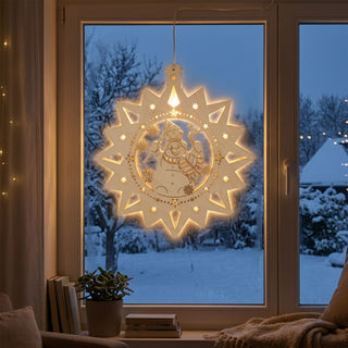 LED‑Fensterbild in Sternform aus naturfarbenem Holz mit Schneemann-Motiv, warm beleuchtet und am Fenster aufgehängt. Im Inneren ist ein fröhlicher Schneemann mit Schal und Mütze zu sehen, umgeben von kleinen Sternen und Winterelementen. Im Hintergrund befindet sich eine verschneite Winterlandschaft; im Raum stehen eine Pflanze, Bücher und eine Decke am Fenster.