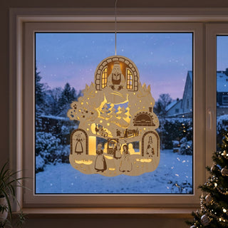 LED‑Fensterbild aus Holz mit Motiv „DEFA – Frau Holle®“, farbig abgesetzt und warm beleuchtet, am Fenster aufgehängt. Dargestellt sind mehrere Szenen aus dem Märchen, darunter die Figur Frau Holle am Fenster, eine Landschaft mit Bäumen und Tieren sowie weitere Figuren rund um Brunnen und Haus. Die Beleuchtung hebt die filigranen Details hervor. Im Hintergrund ist eine verschneite Winterlandschaft zu sehen; im Innenraum stehen eine Pflanze und ein geschmückter Weihnachtsbaum neben dem Fenster.