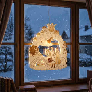 LED‑Fensterbild aus Holz mit Szene aus „Das singende, klingende Bäumchen®“, farbig abgesetzt und warm beleuchtet. Dargestellt sind mehrere Figuren aus dem Märchen, darunter ein Paar neben einem Pferd sowie weitere Figuren und ein Schlossmotiv im Hintergrund. Das Fensterbild hängt vor einer verschneiten Winterlandschaft; innen sind ein Fensterrahmen, Bücher auf der Fensterbank und Vorhänge zu sehen.