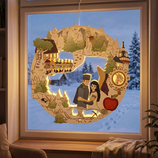LED‑Fensterbild aus Holz mit Motiv „DEFA‑Schneewittchen“, bunt abgesetzt und warm beleuchtet. Im runden Design sind zentrale Märchenszenen dargestellt, darunter ein Paar in der Mitte, die sieben Zwerge, ein Wald mit Tannen, ein Schloss sowie der rote Apfel. Das Fensterbild hängt vor einer verschneiten Winterlandschaft; im Innenraum sind Fensterrahmen, Sessel und eine Pflanze sichtbar.
