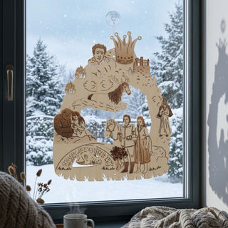 Fensterbild aus naturfarbenem Holz mit Motiv „Das singende, klingende Bäumchen®“, einfarbig abgesetzt und am Fenster aufgehängt. Dargestellt sind mehrere Märchenszenen, darunter Figuren neben einem Pferd, ein schlafender Drache, eine Person mit Krone sowie ein Schloss und Bäume im Hintergrund. Das Fensterbild hängt vor einer verschneiten Winterlandschaft; im Innenraum sind eine Tasse, getrocknete Pflanzen und eine Decke auf der Fensterbank zu sehen.