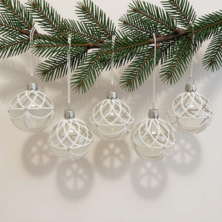 Fünf transparente Christbaumkugeln aus Glas hängen an einem grünen Tannenzweig. Die Kugeln sind mit filigranen weißen Ornamenten aus feinen Perlenlinien verziert, die an Eis- und Schneekristalle erinnern. Zarte matte Elemente und kleine Perlendetails unterstreichen die elegante Gestaltung. Die Kombination aus klarem Glas, weißem Dekor und dem natürlichen Tannengrün verleiht dem 5-teiligen Christbaumschmuck-Set eine winterliche und stilvolle Ausstrahlung.