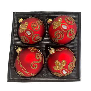 Vier rote Christbaumkugeln aus Glas in einer schwarzen Verpackungseinlage. Die Kugeln sind matt rot beschichtet und mit aufwendigen goldfarbenen Ornamenten verziert. Glitzernde Blütenmotive, geschwungene Perlenlinien und klare, facettierte Schmucksteine setzen elegante Akzente. Das harmonische Zusammenspiel von Rot und Gold verleiht dem 4-teiligen Christbaumschmuck-Set eine festliche und luxuriöse Ausstrahlung.