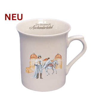 Weißer Porzellan-Kaffeebecher mit Henkel und dem Schriftzug „Drei Haselnüsse für Aschenbrödel®“ am oberen Innenrand. Auf der Vorderseite ist eine detailreiche Illustration aus dem Märchenfilm zu sehen: Aschenbrödel auf einem weißen Pferd, der Prinz mit Schuh in der Hand, im Hintergrund Schloss Moritzburg. Der Becher ist aus glattem Porzellan gefertigt und klassisch geformt.