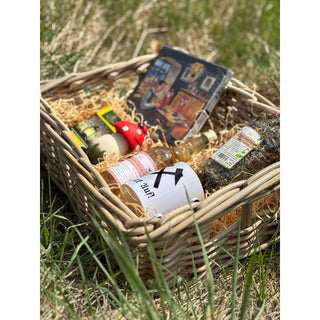Präsentkorb „Himmelfahrt“ von SAICO mit geflochtenem Korb, Kaffeetasse „Glück auf“, Kräuterlikör, Kräutertee aus dem Erzgebirge, Räucherfigur Räucherpilz, Räucherkerzen „Ruhe“ und Servietten, dekorativ in Holzwolle arrangiert. Auf einer Wiese dekoriert.