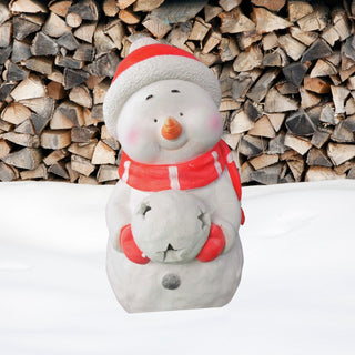 Dekofigur „Schneemann mit LED‑Schneeball“, 41 cm hoch, mit roter Mütze und rotem Schal, Karottennase und roten Handschuhen, hält einen Schneeball mit integrierter LED‑Beleuchtung vor dem Körper, aufgestellt im Schnee vor einem Hintergrund aus gestapeltem Brennholz, geeignet für stimmungsvolle Weihnachtsdekoration mit Timerfunktion.