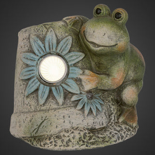 Keramikfrosch mit integrierter LED‑Solar‑Leuchte, 12 cm hoch, sitzend an einem steinähnlichen Element mit dekorativen Blumen, detailreich gestaltet in Grün‑ und Naturtönen.