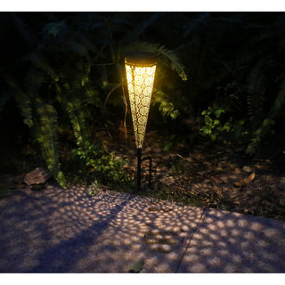 Braunfarbene Solarlaterne aus Metall mit Bodenspieß, 40 cm hoch, leuchtend bei Nacht im Gartenbeet und erzeugend ein warmes Lichtmuster auf dem Boden.