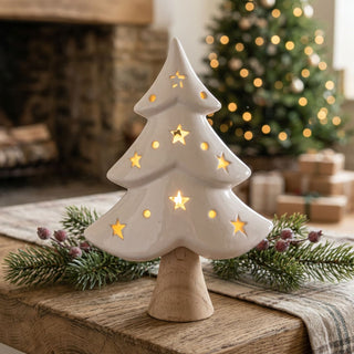 LED Keramikbaum (21 cm) mit Holzstamm, warmweiß beleuchtet, weiß glasierte Oberfläche mit ausgestanzten Sternen und Punkten, als stimmungsvolle Tischdekoration in gemütlicher Weihnachtsatmosphäre.