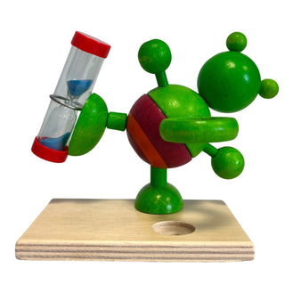 Rückansicht der Zahnputzuhr „Frosch“ aus farbig bemaltem Holz, grüne Froschfigur mit rundem Körper und integrierter Sanduhr im ausgestreckten Arm, auf rechteckigem Holzsockel, Höhe 11 cm.