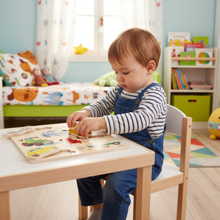 Kleinkind spielt konzentriert mit buntem Holz-Steckpuzzle am Kindertisch – selbstständiger Lernmoment im freundlichen Kinderzimmer"