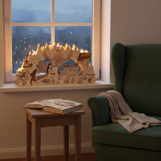 Kerzenhalter aus Holz für fünf Teelichte mit Motiv „DEFA‑Schneewittchen“, farbig abgesetzt, auf einer Fensterbank platziert. Die detailreiche Szene zeigt zentrale Märchenfiguren im Vordergrund, umgeben von Wald, Häuschen und weiteren Elementen aus der Geschichte. Fünf brennende Teelichter sorgen für warmes Licht und bringen die filigranen Details zum Leuchten. Im Hintergrund ist ein Fenster mit verschneiter Winterlandschaft zu sehen; daneben stehen ein Sessel und ein kleiner Tisch mit Buch.