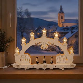 LED-Schwibbogen „Kurrende“ aus naturfarbenem Holz mit drei traditionellen Sängerfiguren zwischen stilisierten Stadthäusern. Zehn warm leuchtende LED-Lichter im Bogen sorgen für eine festliche Beleuchtung und setzen die filigrane 3D-Gestaltung stimmungsvoll in Szene. Der 47 cm breite Schwibbogen ist ein klassisches Beispiel erzgebirgischer Weihnachtskunst.