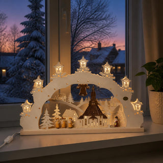 LED-Schwibbogen „Seiffener Kirche“ aus naturfarbenem Holz mit detailreicher Darstellung der berühmten Seiffener Kirche. Unter dem beleuchteten Bogen befinden sich eine Sängergruppe, ein Nachtwächter sowie verschneite Häuser und Tannenbäume. Die warmweiße LED-Beleuchtung in den Laternen und hinter dem Motiv sorgt für eine stimmungsvolle Tiefenwirkung. Der 52 cm breite Schwibbogen steht auf einer Fensterbank vor einer winterlichen Abendkulisse und schafft eine festliche Weihnachtsatmosphäre.