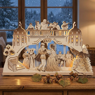 LED Schwibbogen „Drei Haselnüsse für Aschenbrödel®“ Limited Edition 2024 aus Holz mit beleuchteter Tanzszene und märchenhaften Motiven. Der 52 cm breite Schwibbogen steht vor einem verschneiten Fenster und verbreitet warmes Weihnachtslicht.