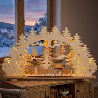 LED Schwibbogen „Waldidylle“ aus naturfarbenem Holz mit filigraner Waldszene und geschnitzten Rehen an einer Futterkrippe. Der 68,5 cm breite Lichterbogen zeigt Tannenbäume, Sterne und Waldtiere, die von warmweißen LEDs stimmungsvoll beleuchtet werden. Die detailreiche Gestaltung schafft eine gemütliche und winterliche Weihnachtsatmosphäre.