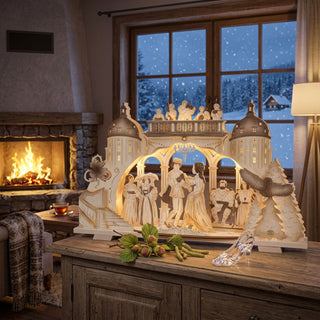 Premium-Line Schwibbogen „Drei Haselnüsse für Aschenbrödel®“ Limited Edition 2024 aus Holz mit beleuchteter Ballszene. Der 70 cm breite Schwibbogen steht in einem gemütlichen Wohnzimmer vor einem verschneiten Fenster und wird stimmungsvoll von warmem Licht in Szene gesetzt.