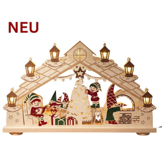 LED‑Schwibbogen „Wichtel‑ und Elfenland“ aus farbig gestaltetem Holz mit beleuchteten Laternen, Weihnachtsbaum, Geschenken und spielenden Wichtel‑ und Elfenfiguren; 69 cm breit.
